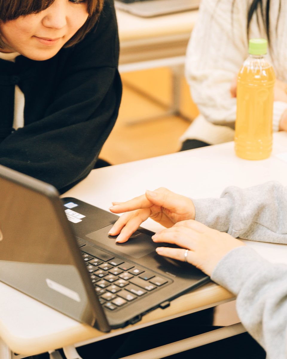 3人がノートPCの画面を一緒に見ながら、手元を指し示して相談している様子