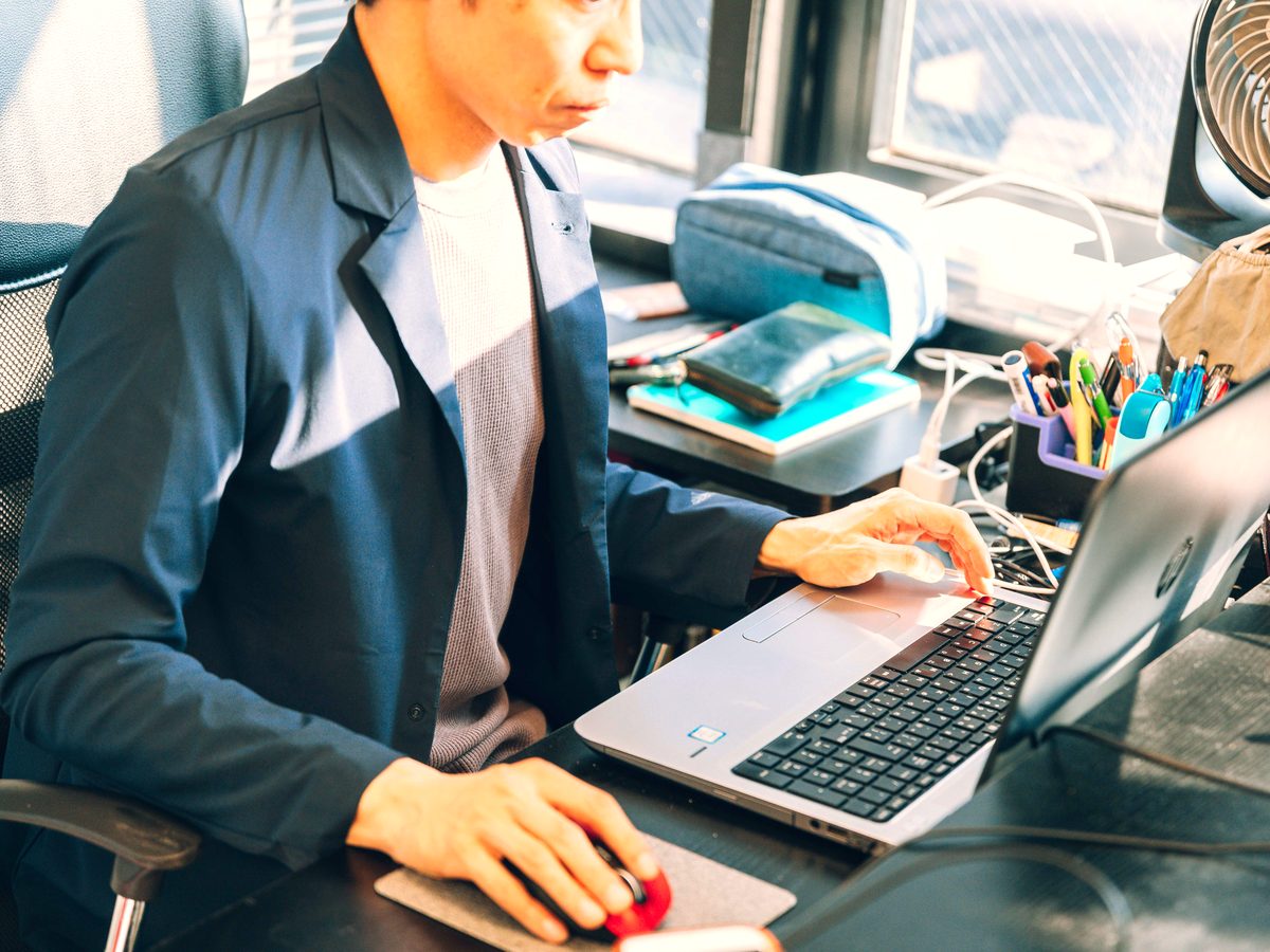 デスクでノートPCとマウスを操作しながら、実際に設定作業を行っている様子